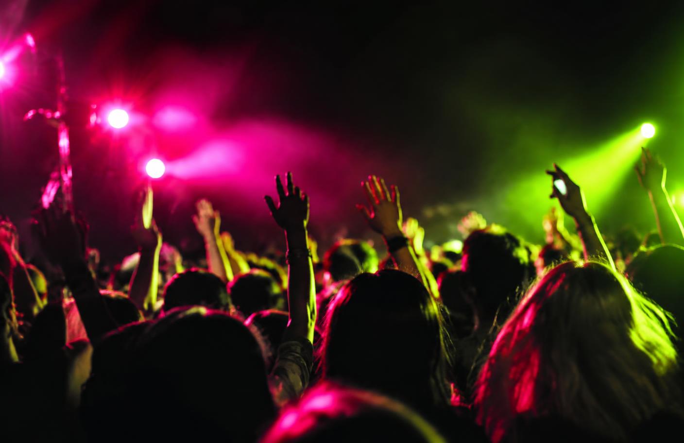A crowd moving under pink and chartreuse lights